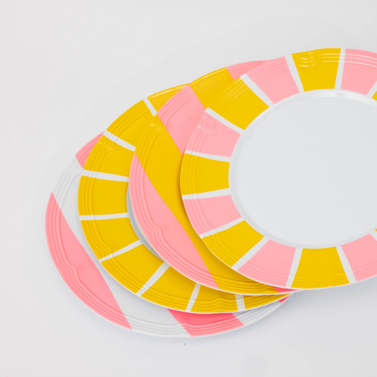 Stack of colorful paper plates with pink and yellow stripes on a white background